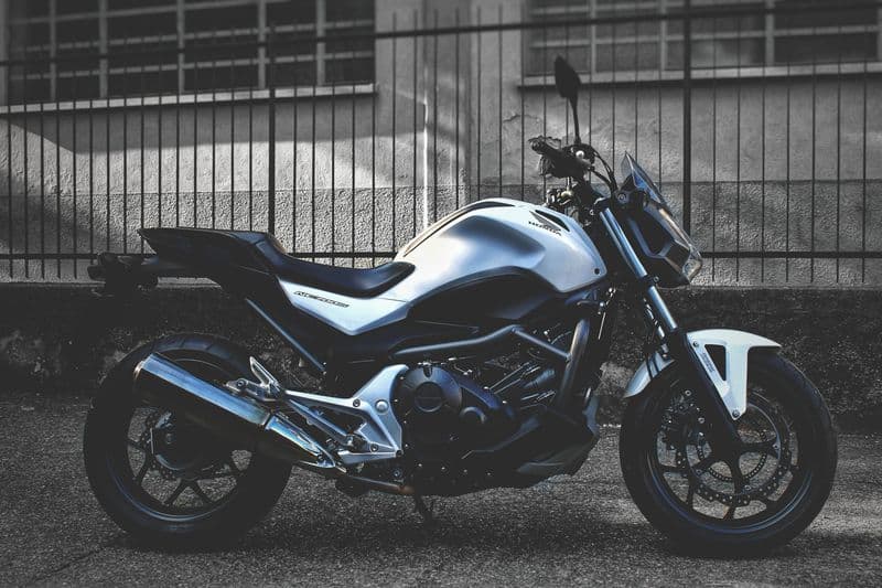 Moto prata estacionada em frente a uma grade